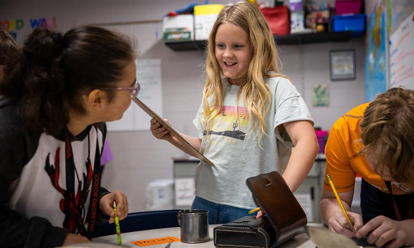 A girl wearing a t-shirt smiles while exploring historical items